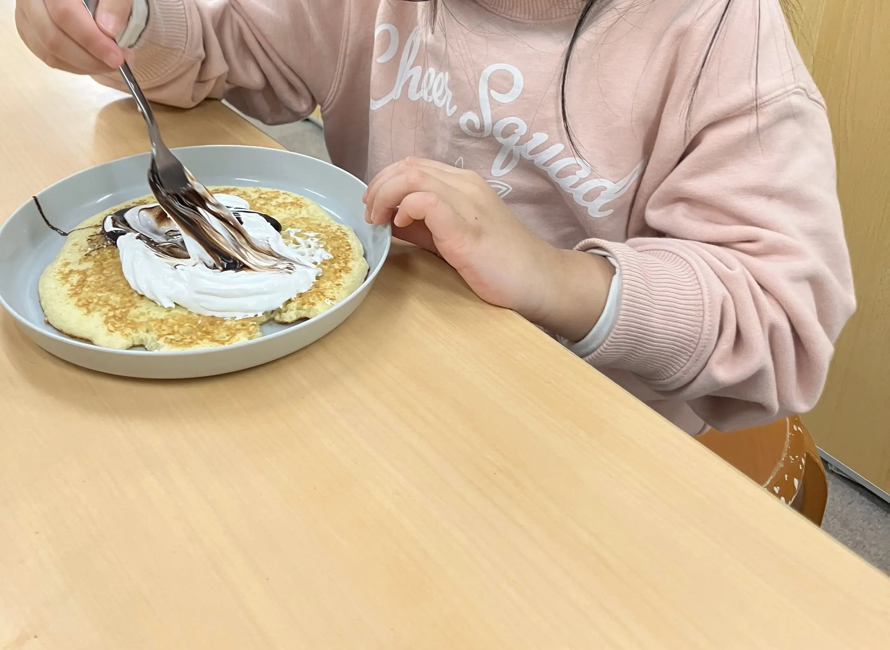 ロールケーキに生クリームとチョコソースをつけている場面